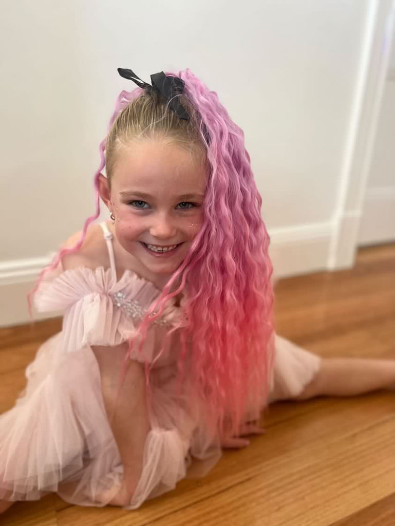 a little girl is sitting on a floor by wearing Coral Wavy Mermaid Ponytail